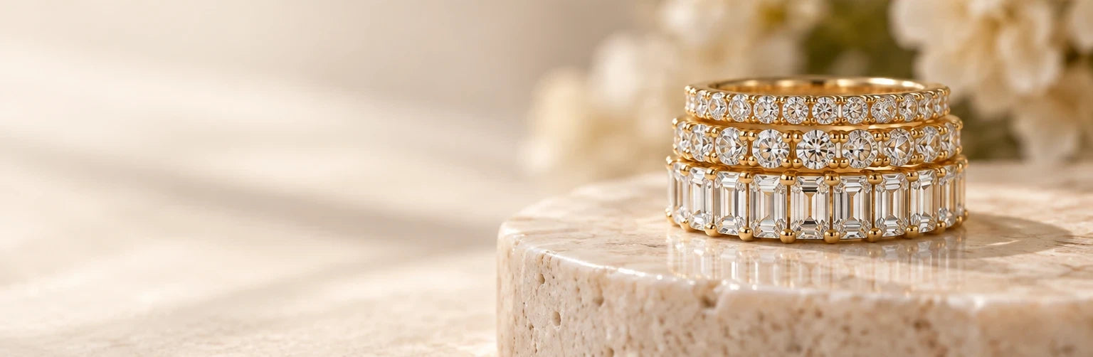 Stack of three yellow gold diamond bands on a travertine pedestal